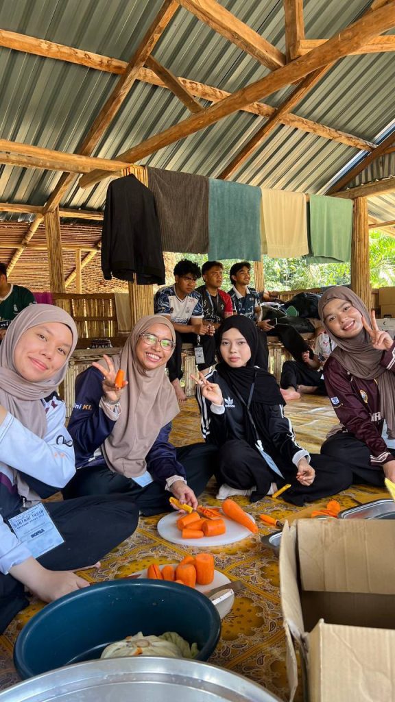Students and children posing together during an Orang Asli community outreach programme in Sungai Siput, Perak.