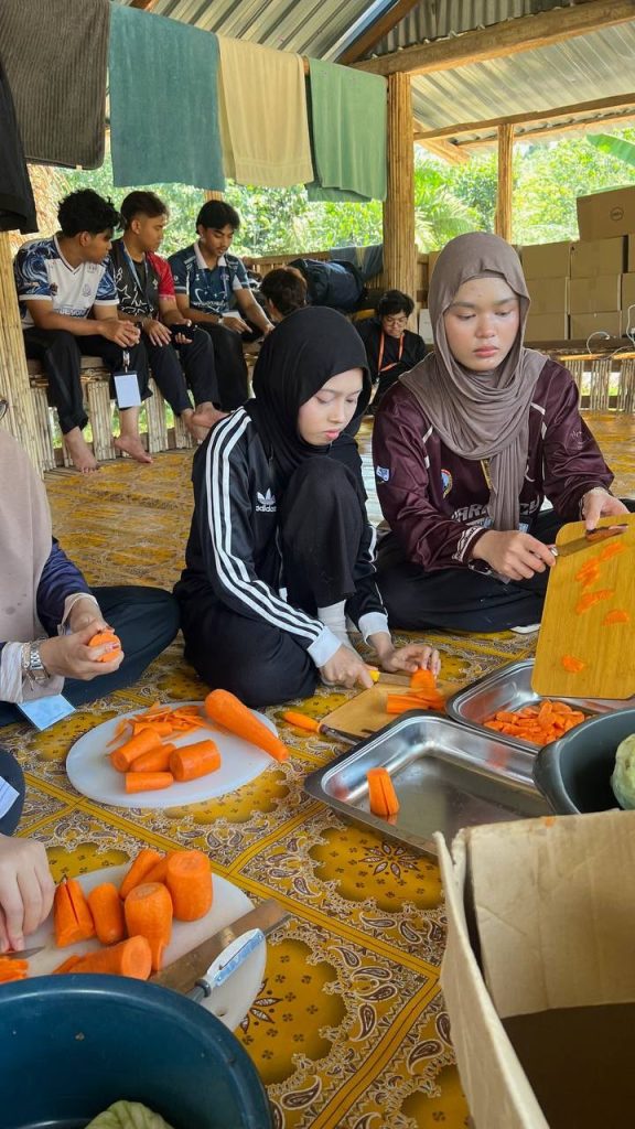 Volunteers preparing vegetables and food together during an Orang Asli community outreach programme.